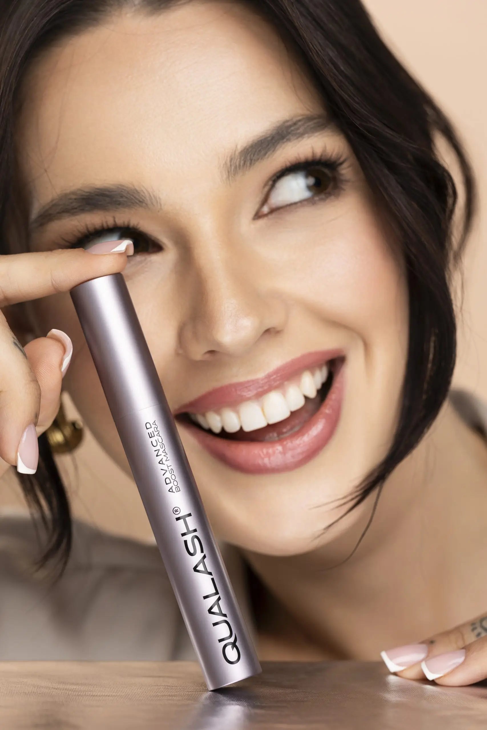 Woman applying QUALASH Advanced Mascara Volume Max to upper lashes using precision brush – Step 1