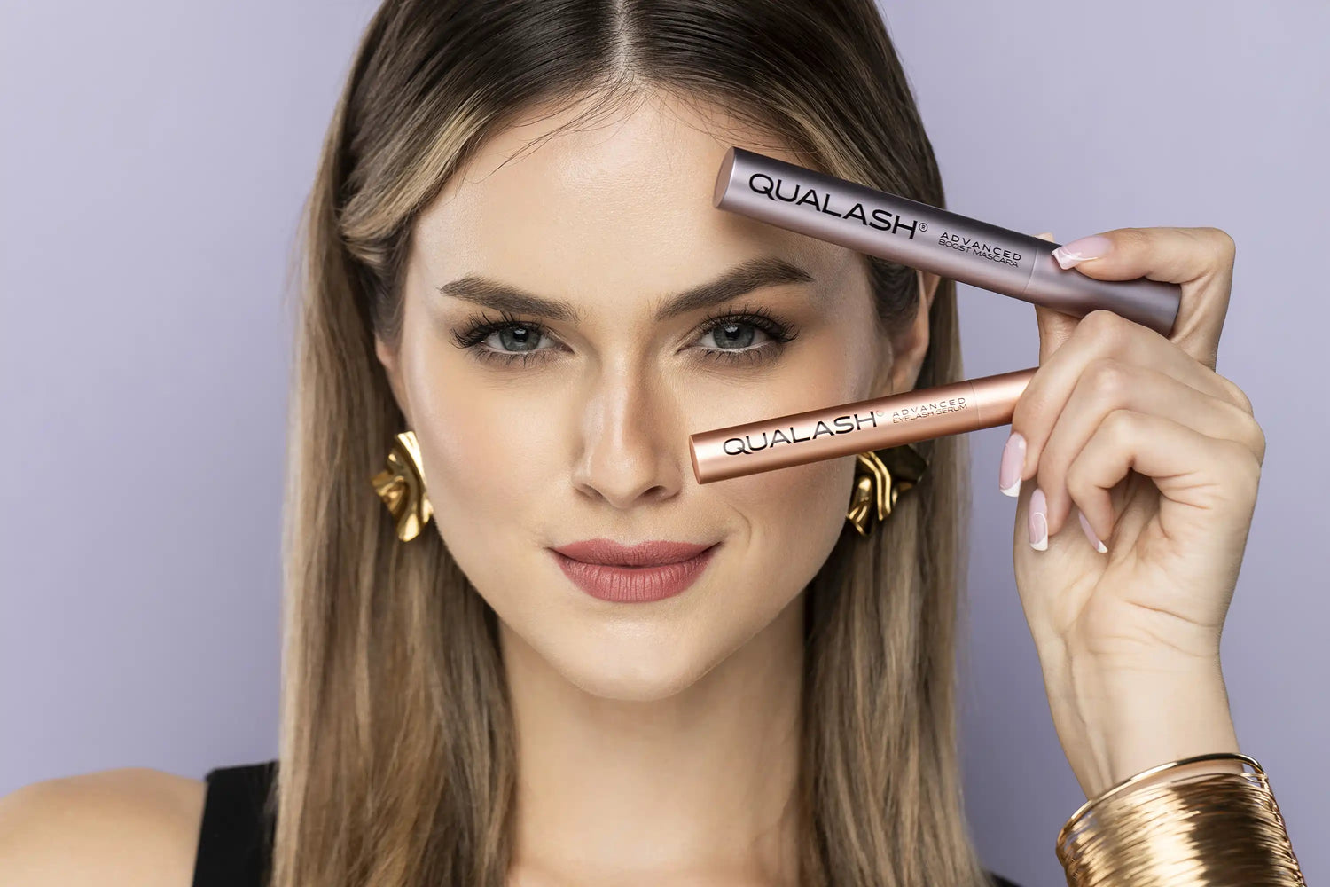 Woman holding QUALASH essence ritual set – eyelash serum and peptide mascara volume max